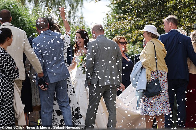 Dashing bride Michelle Dockery looked overjoyed as her guests threw confetti today