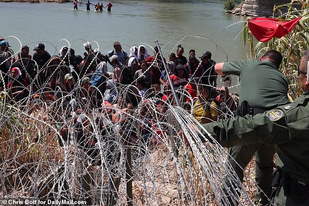 The migrants rushed forward together and crowded onto a bank on the American side, where they refused to move for two hours as they tried to find a way through the barbed wire.