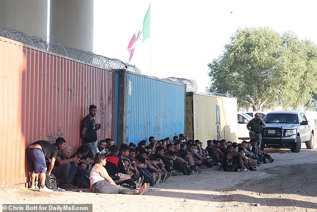 Photos from DailyMail.com show the group of migrants waiting in line before being processed under the Camarillo Real International Bridge