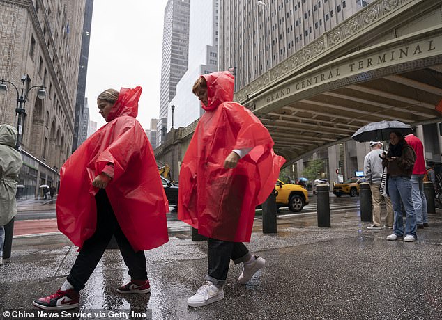 People wearing raincoats walk on the street on a rainy day in New York