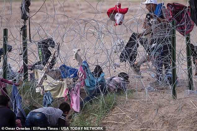 Migrants break through concertina wire constructed by the Texas National Guard on the border between Ciudad Juarez and El Paso