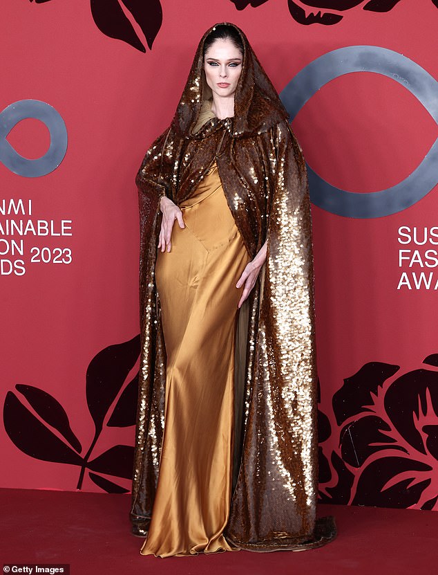 Dramatic: Model Coco Rocha stunned in a gold satin dress which she paired with a matching sequined hooded cape