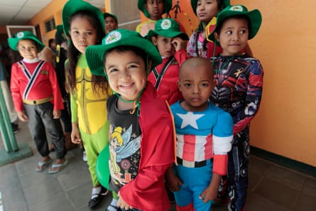 Children dressed in superhero costumes with green hats pose for the camera.