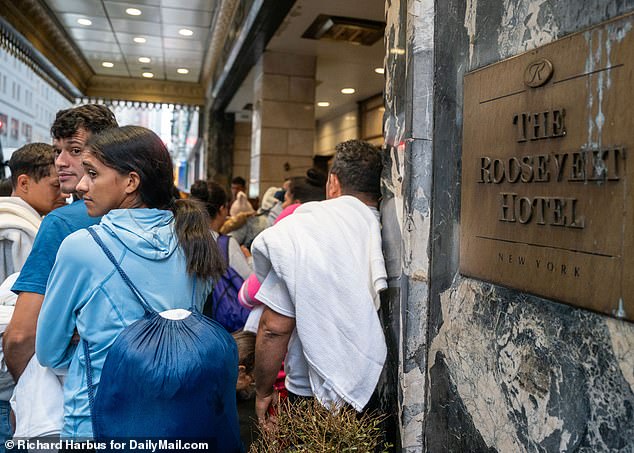 Migrants, most from Venezuela, wait outside the Roosevelt Hotel to be processed