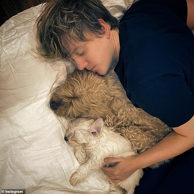 The 36-year-old comedian is pictured cradling his pet in bed