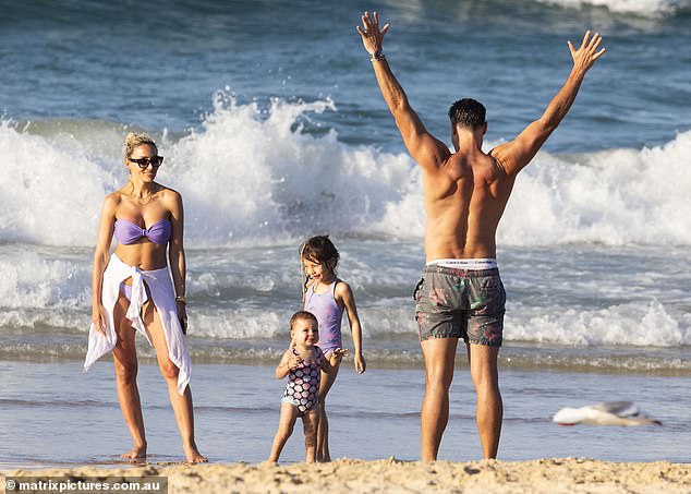 Her husband Sam also showed off his toned physique in printed shorts as he spent time with his daughters on the beach