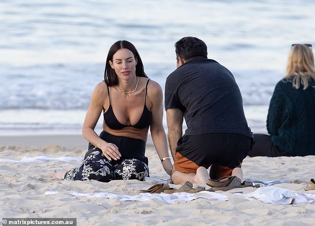 Alex showed off her incredible figure in a bikini top and flared pants as she relaxed in the sand with Doctor Shridharani