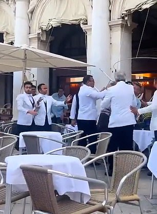 The men are seen kicking and punching each other, while one man held a chair in front of his chest, apparently to protect himself (photo above)