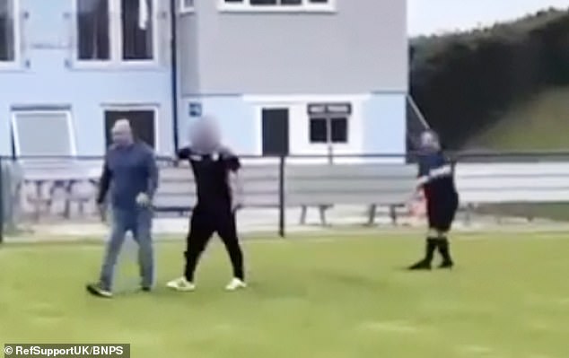 The video shows an angry dad, who was acting as a linesman, chasing Mr Hughes before being dragged away from him by another parent (pictured)