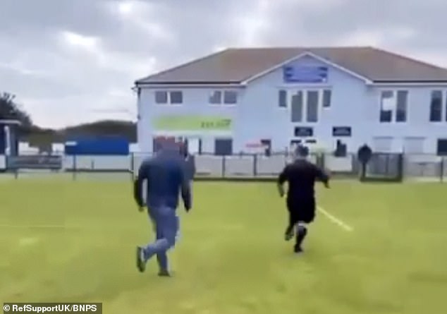 The video shows the burly man, wearing jeans and a blue top, sprinting across the field as Mr Hughes runs away