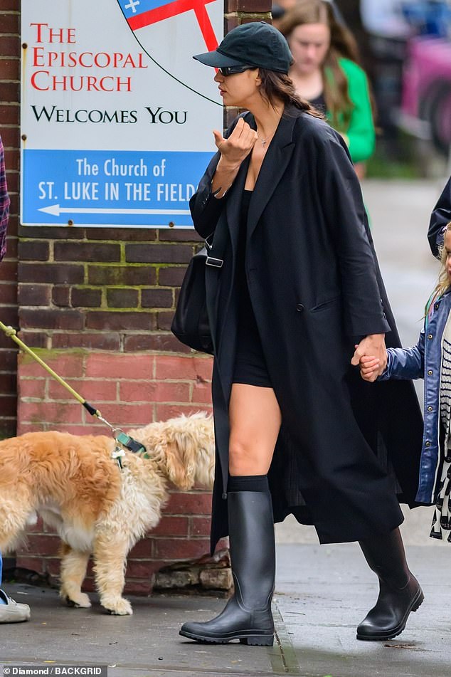 Chic: Irina paired her dress with a chic black coat and handbag, with her locks pinned up under a black cap