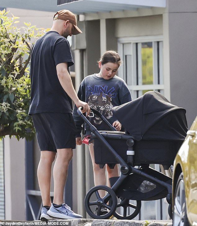 Harper and her father stare into the newborn's stroller during their family outing