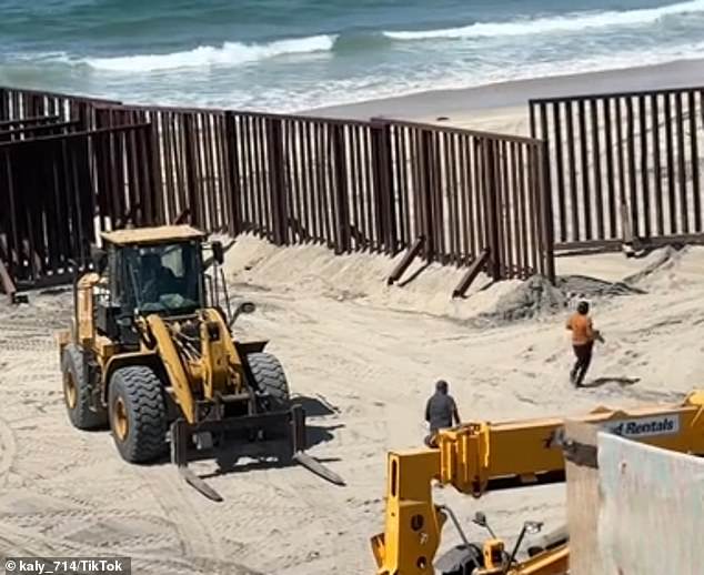 Undocumented migrants run toward an open steel barrier on the U.S. side of the U.S.-Mexico border