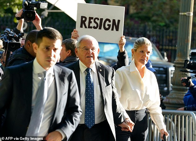 A protester holds a sign as the senator and his wife arrive at the court