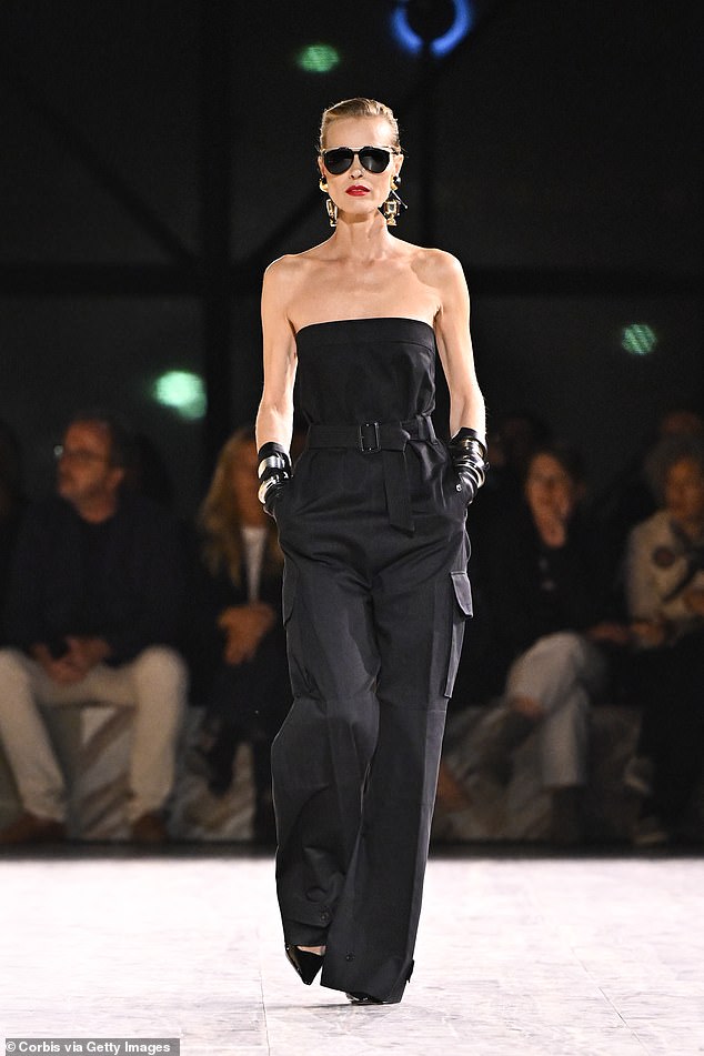 Supermodel moment: Eva Herzigova, 50, turned heads in a black strapless jumpsuit as she graced the runway at the Yves Saint Laurent show during PFW