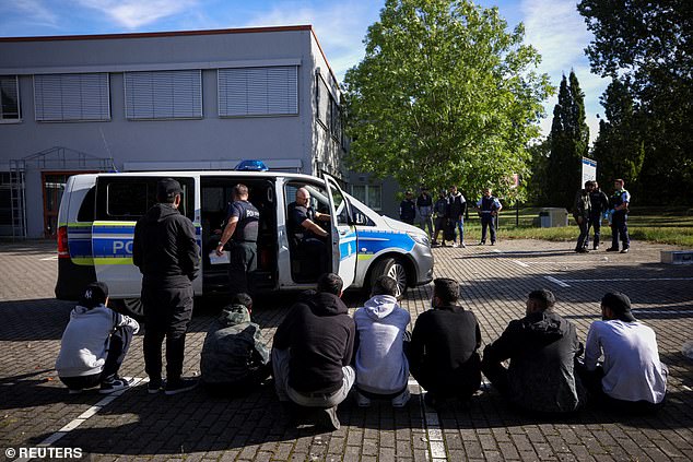 Suspected illegal migrants sit on the ground after being detained by German police during their patrol along the German-Polish border to prevent illegal migration, in Forst, Germany, September 20, 2023