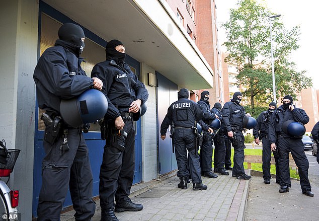 Police officers on duty during a raid stand in front of an apartment building in Stade, Germany, Tuesday, September 26, 2023. During raids in five states, officers discovered several Syrians suspected of being smuggled in early Tuesday morning.