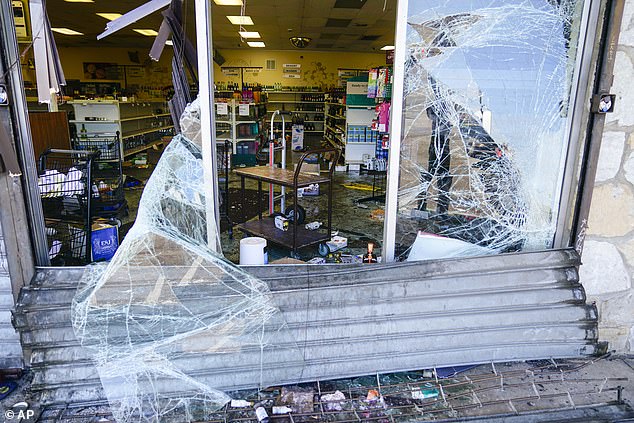 The windows of a looted liquor store were shattered and hung from pieces of glass