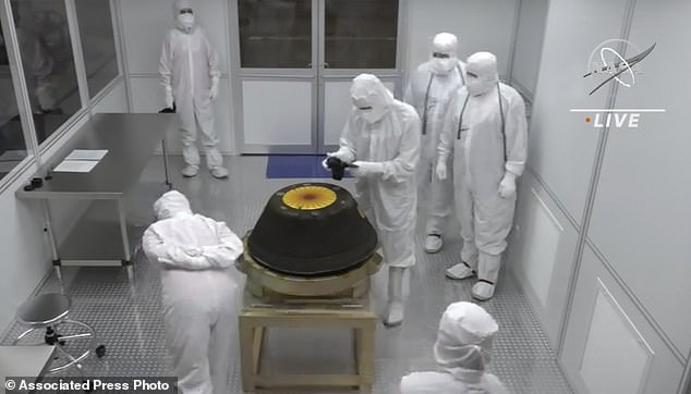 In this image from a NASA video, technicians in a clean room examine the sample return capsule of NASA's Osiris-Rex mission after it landed