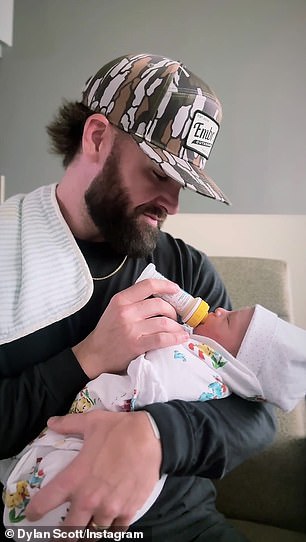 On Thursday morning, Scott (last name Robinson) shared an adorable video of himself bottle-feeding little Barron while promoting his new single I'll Be A Bartender, out October 6.