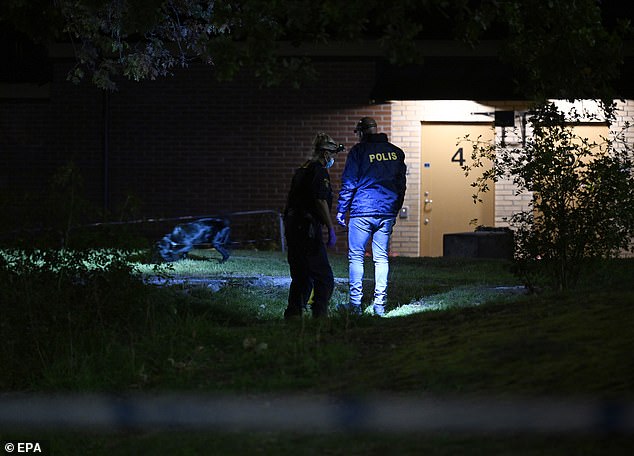 Police officers investigate the scene where a young man was shot on a sports field in southern Stockholm, Sweden, on Wednesday evening