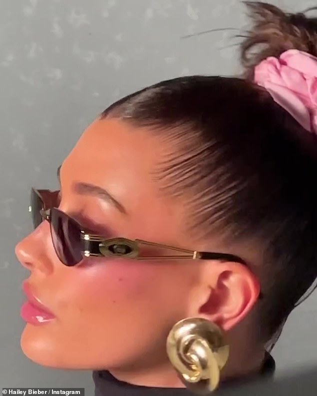 Views: Includes a video of herself wearing a pink blush, pink glossy lips, a large pink scrunchie in her hair, and gold and black sunglasses with statement earrings