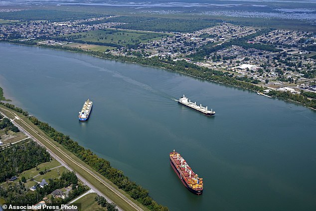 A tanker ship travels downstream near dredging operations on the Mississippi River