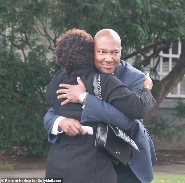 Duroseau (pictured hugging a family member) held a press conference about his decision to file the lawsuit along with 18 other plaintiffs