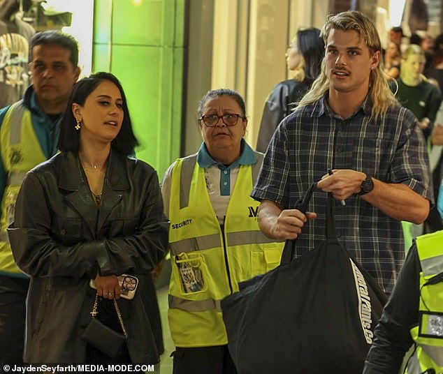 The 22-year-old was dressed casually in a flannel button-up shirt and was escorted out by a security team as he left the event with the brunette.