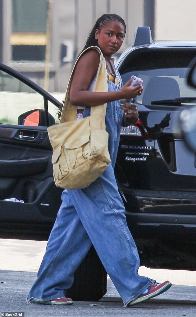 Sasha showed off her bohemian style in baggy Dickies overalls, which she wore over a cropped white shirt and cherry print shorts that poked out the side