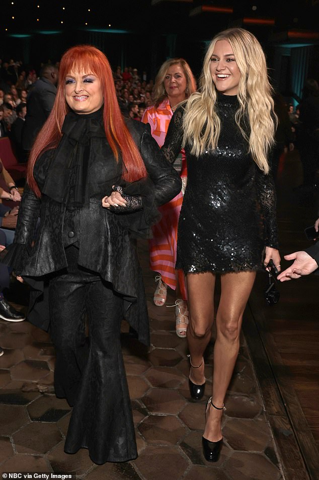 Round time: The country music legend showed off her layered leather look while holding hands with singer-songwriter Kelsea Ballerini, who showed off her figure in a black sequin mini dress