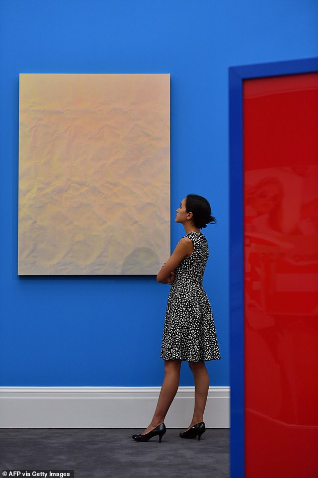 A woman poses with a work of art by Tauba Auerbach – one of the first artists in which Simchowitz invested