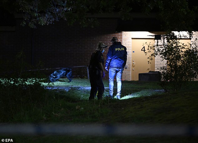 Police officers investigate the scene where a young man was shot on a sports field in southern Stockholm on Wednesday evening