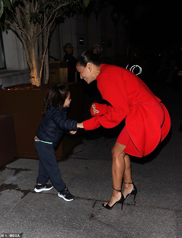 Funny moment: Longoria and her boy were spotted just outside their hotel in Paris sharing a funny moment as he put his hand in the cuff of his mother's eye-catching red knitted mini dress