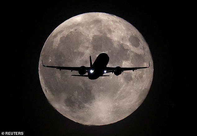 A plane passes in front of the Harvest supermoon last night as it lands towards London's Heathrow Airport