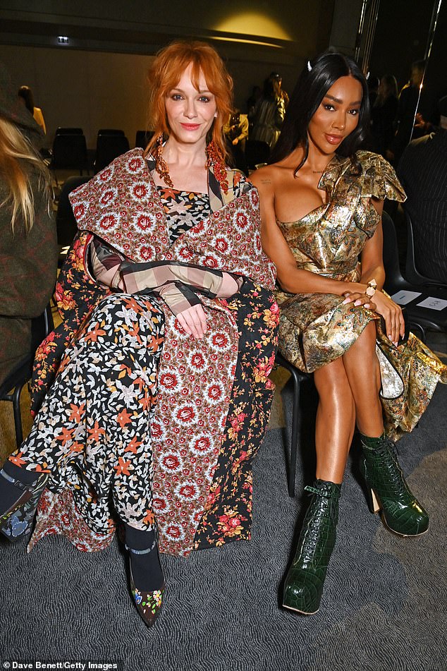 Friends: Actress Christina cut a fashionable figure in a dramatic mixed print dress and matching cape as she joined Munroe Bergdorf (right) in the front row