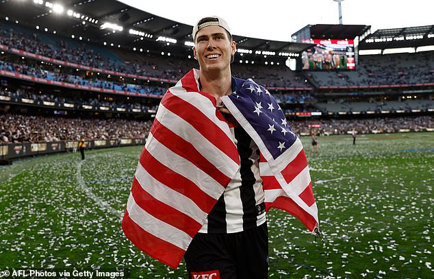 Mason Cox adorns himself with the flag of the United States after becoming the first American to win the AFL premiership