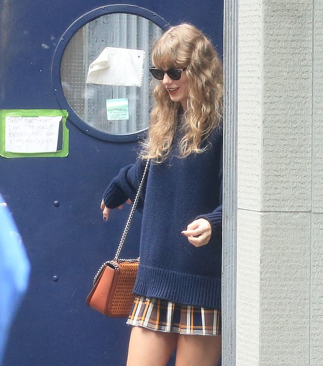 Accessory: Taylor carried an orange-colored bag with a silver chain strap over her shoulder