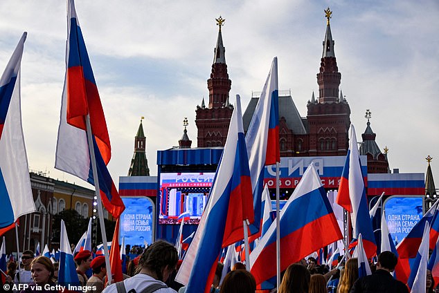 People waving Russian flags attend a concert marking the first anniversary of the annexation of four regions in Ukraine controlled by Russian forces