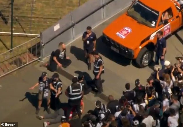 Three climate protesters wearing T-shirts saying 'Can't play football in 50 degrees' blocked the annual AFL Grand Final parade (pictured)