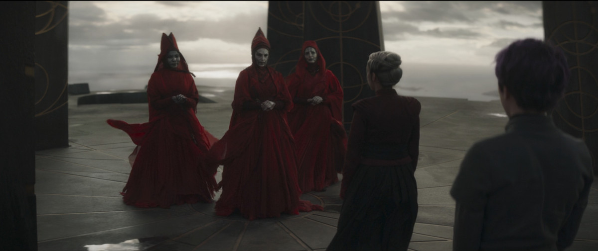 The witches of Dathomir standing with clasped hands, looking at Elsbeth