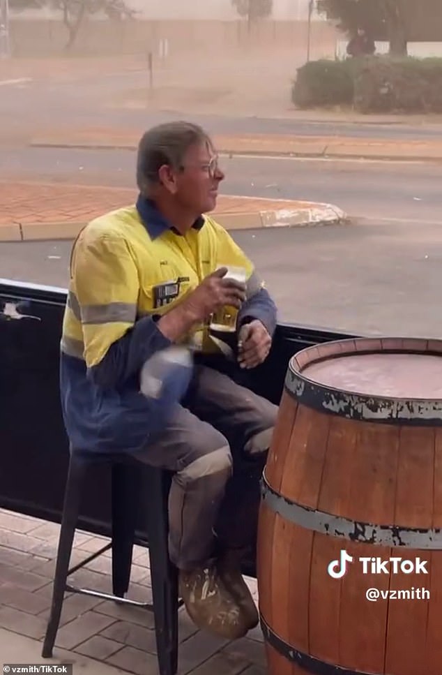 Footage shows the man in high vis stoically holding a pint as tables and chairs fly around the outdoor area of ​​a pub in Kalgoorie-Boulder, Western Australia