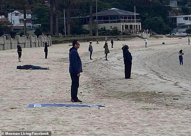 The strange photo shows a group of people dressed in black standing separately from each other, not moving and staring into the waves