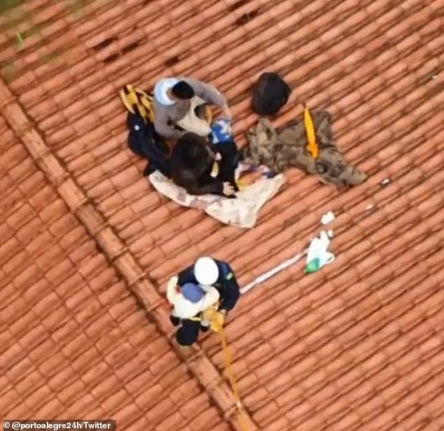 A police officer prepares to evacuate a child from a rooftop in the southern Brazilian city of Roca Sales on Tuesday, a day after an extratropical cyclone hit the state of Rio Grande do Sul, killing 22 people