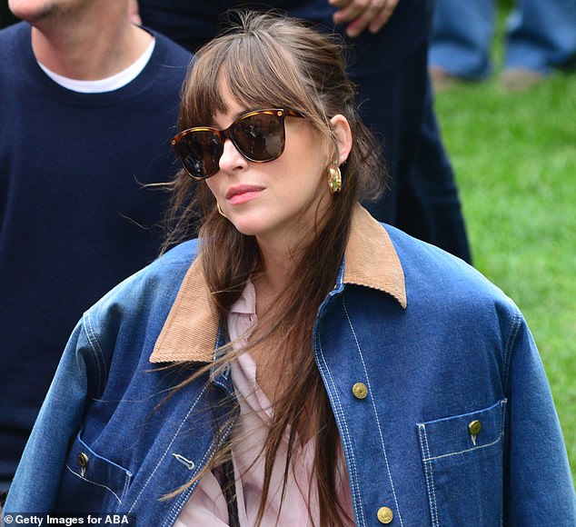 The 50 Shades Of Gray actress wore a chic denim jacket over a loose-fitting pink button-up shirt that she tied at the bottom to show off her waist