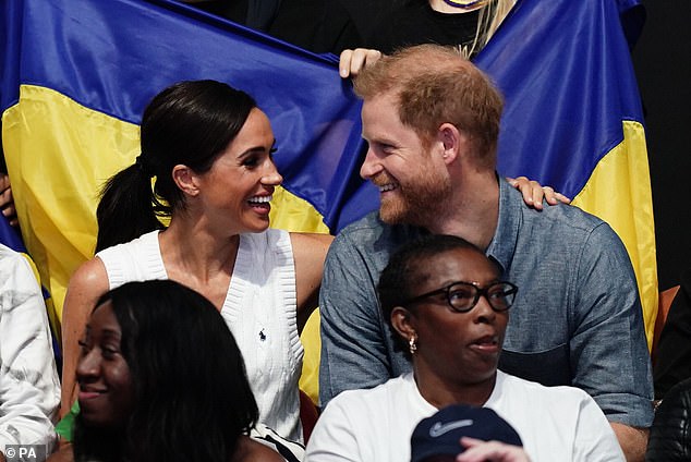 The smiling Duchess of Sussex puts her arm around her husband Prince Harry during yesterday's games