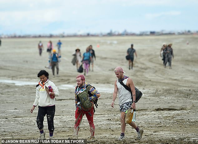 People walk down the playa near the Burning Man site in northern Nevada's Black Rock Desert after the torrential rain