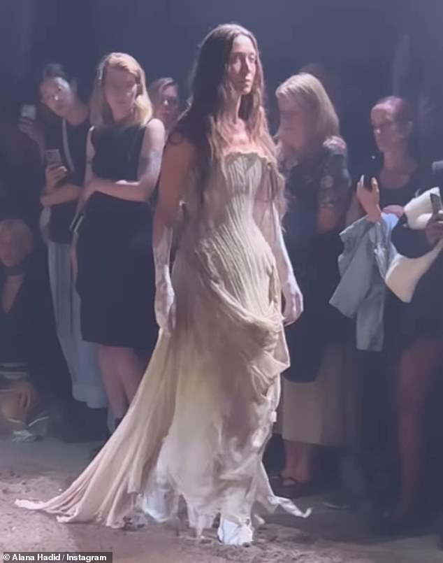 New look: The model walked the runway at the Elene Velez show on Tuesday in a ripped beige corset-style dress accessorized with lace gloves and white knee-high boots.  She also had white paint on her arms'