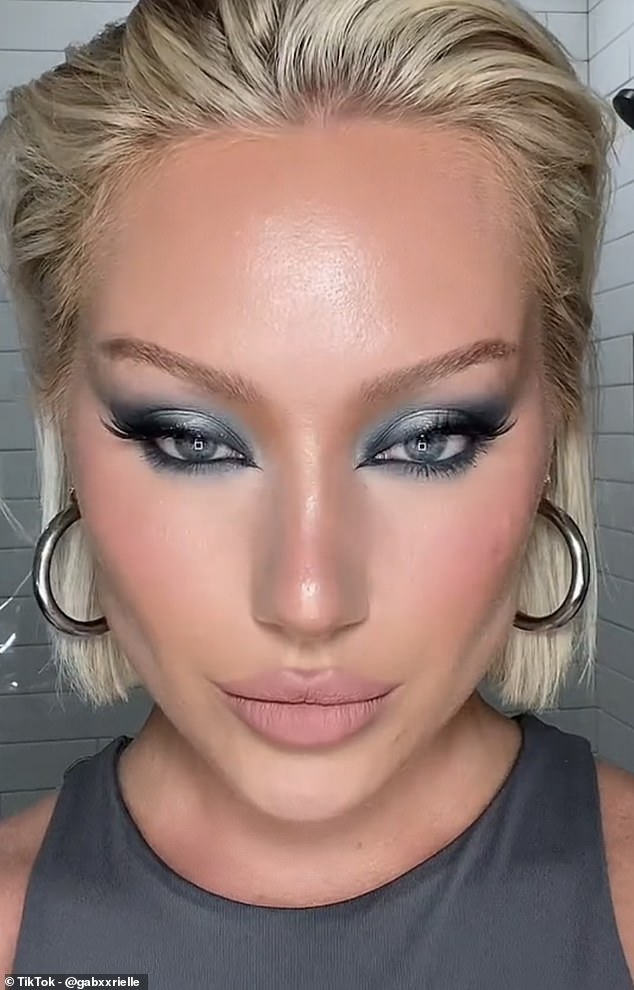 Another TikTok makeup creator, Gabrielle (pictured), showed off her version of the look, combining a bold, smokey eye with chiseled cheeks, plump lips and a dewy, glowy complexion