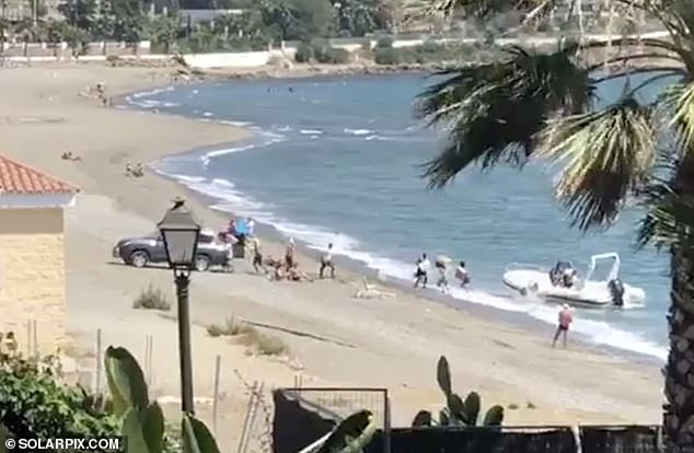 A drug gang carries bags allegedly containing cannabis resin from a speedboat (right) to a parked car (left) on Spain's Costa del Sol in 2019